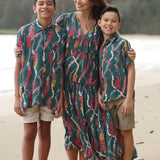 little boy wearing aloha button up shirt in dark teal with shell and lei print