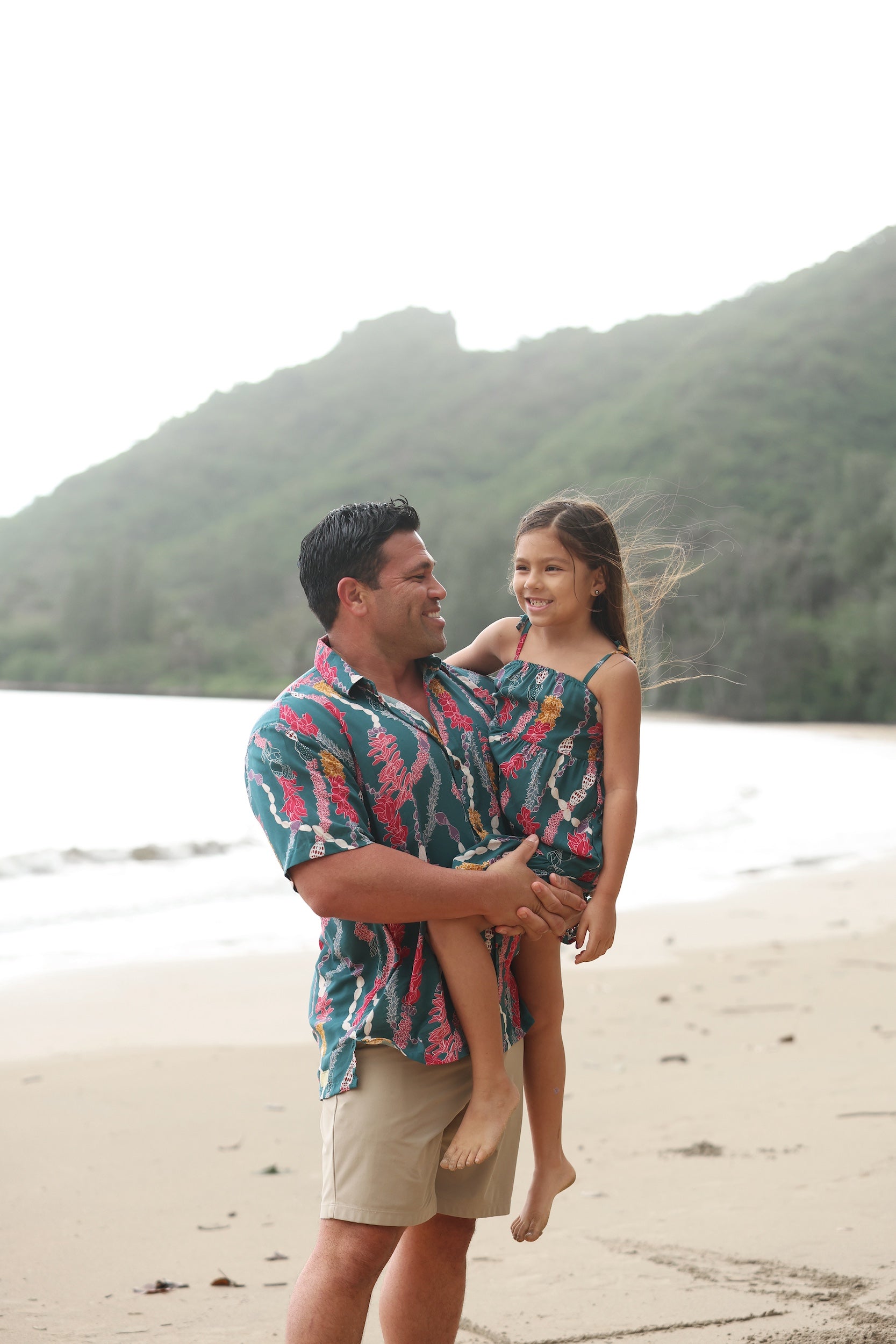 little girl wearing a knee length dress with tie spaghetti straps in dark teal with shell and lei print