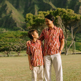 boy wearing red-brown aloha button up shirt with lei print