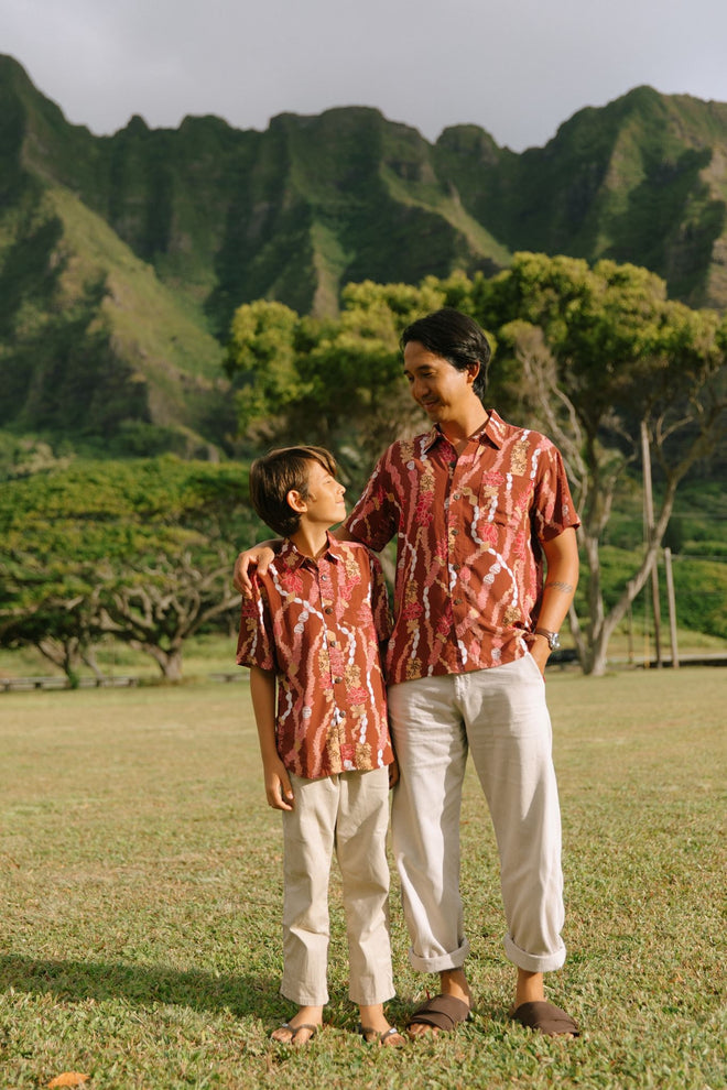 boy wearing red-brown aloha button up shirt with lei print