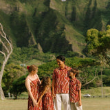 man with black hair wearing a red-brown aloha button up shirt with lei print