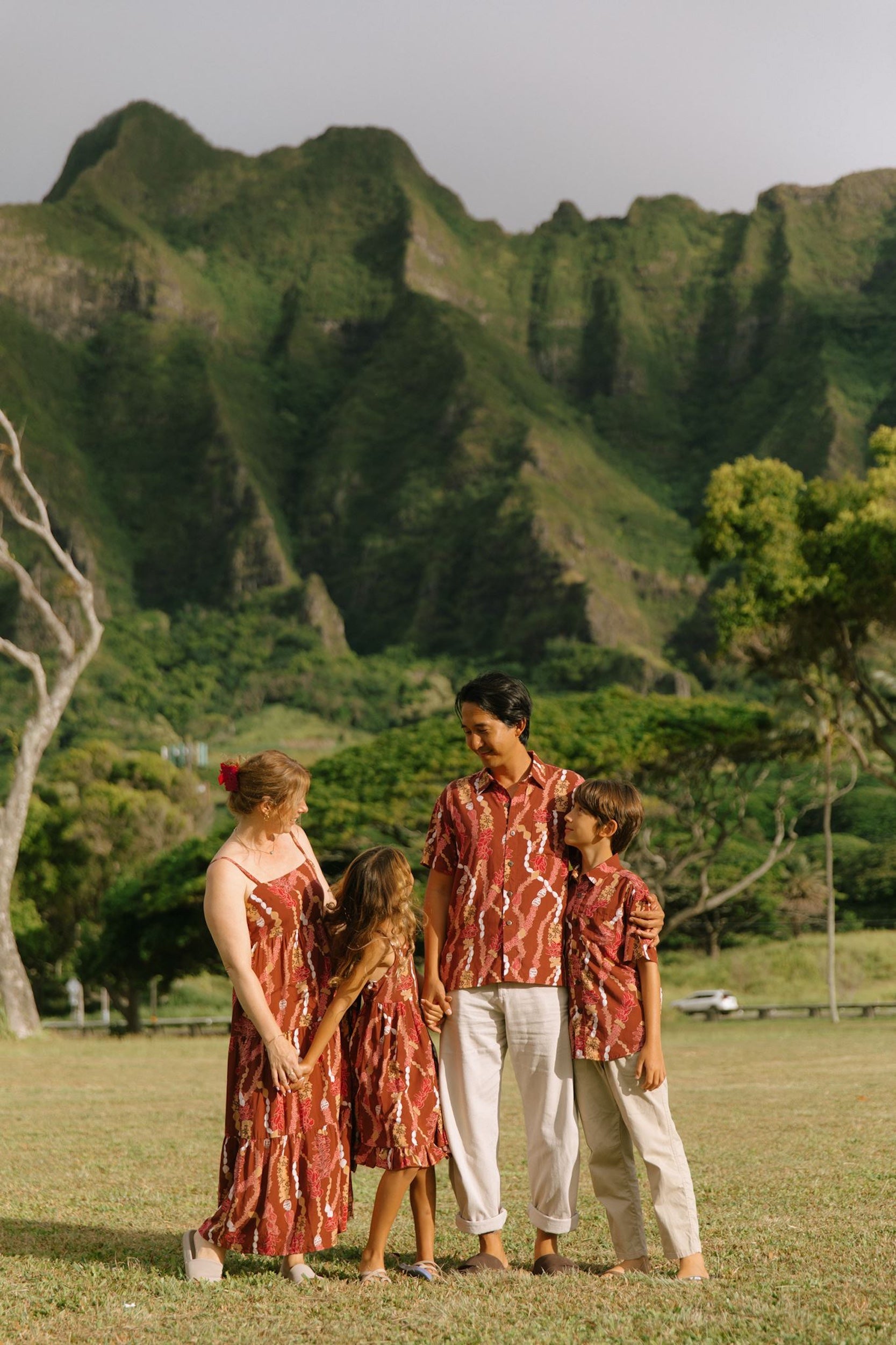 man with black hair wearing a red-brown aloha button up shirt with lei print