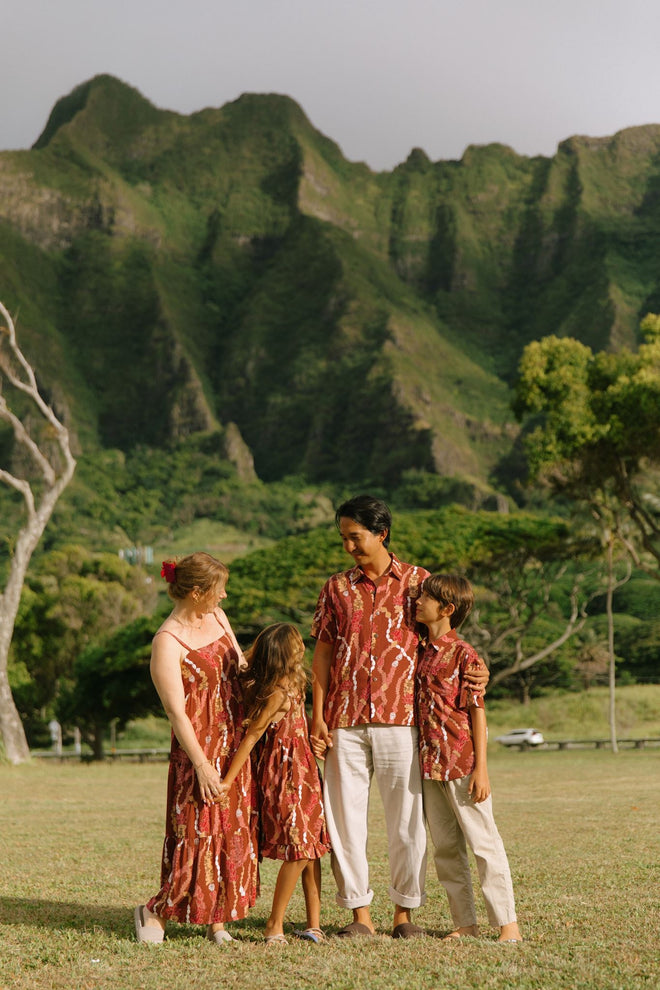 man with black hair wearing a red-brown aloha button up shirt with lei print