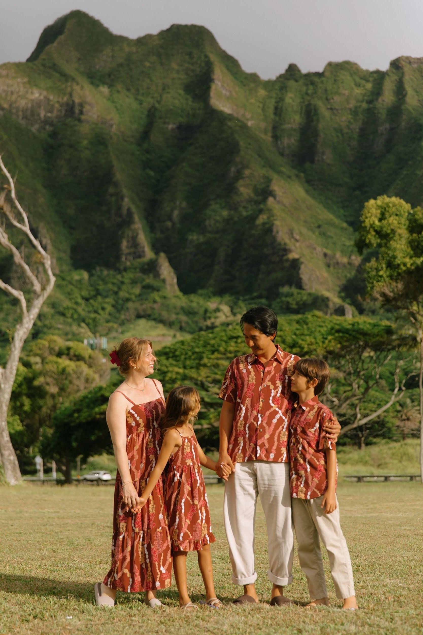little girl wearing a red-brown tie back dress with ruffle hem and lei print