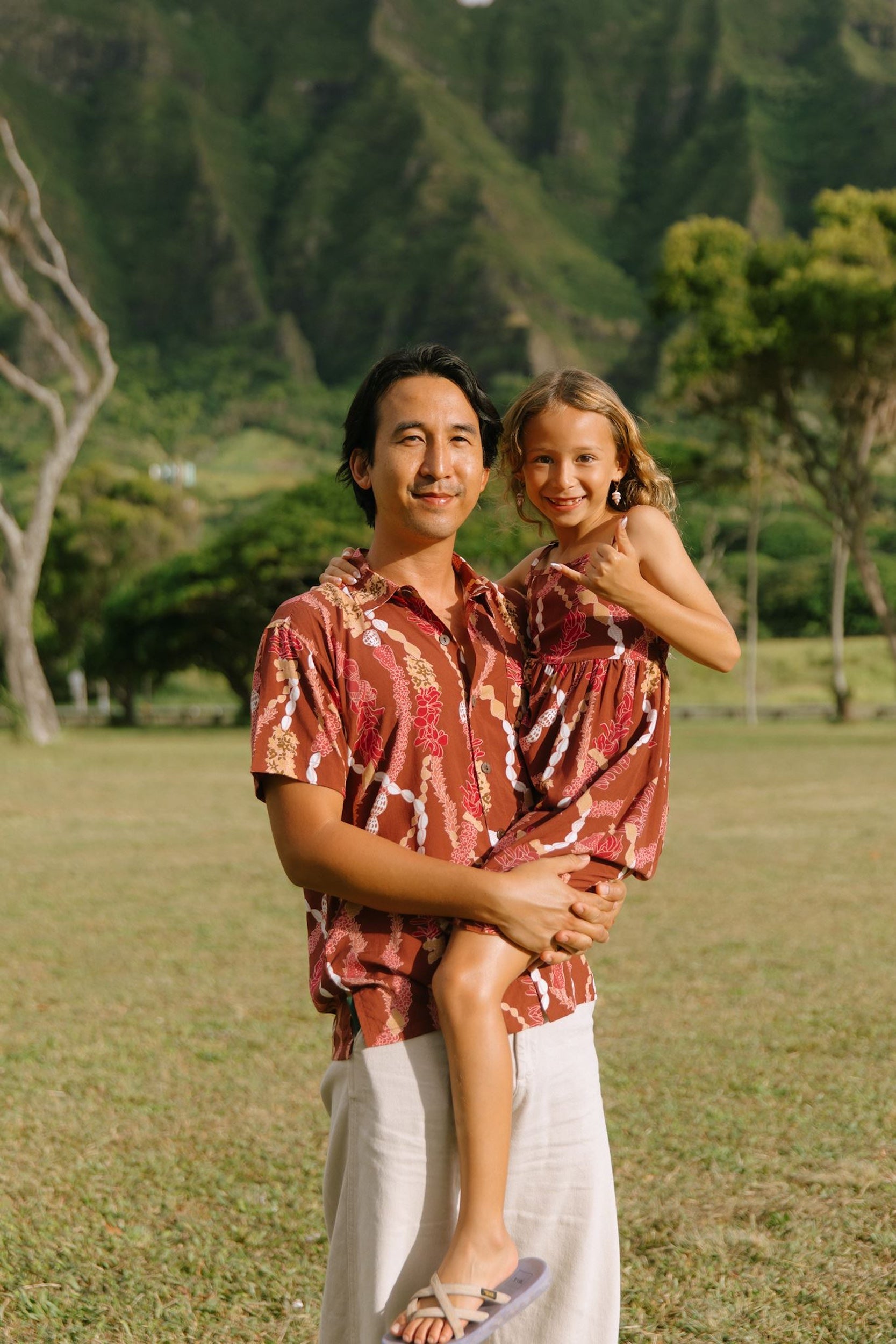 man with black hair wearing a red-brown aloha button up shirt with lei print