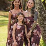 little girl wearing brown high neck, sleeveless dress with protea print