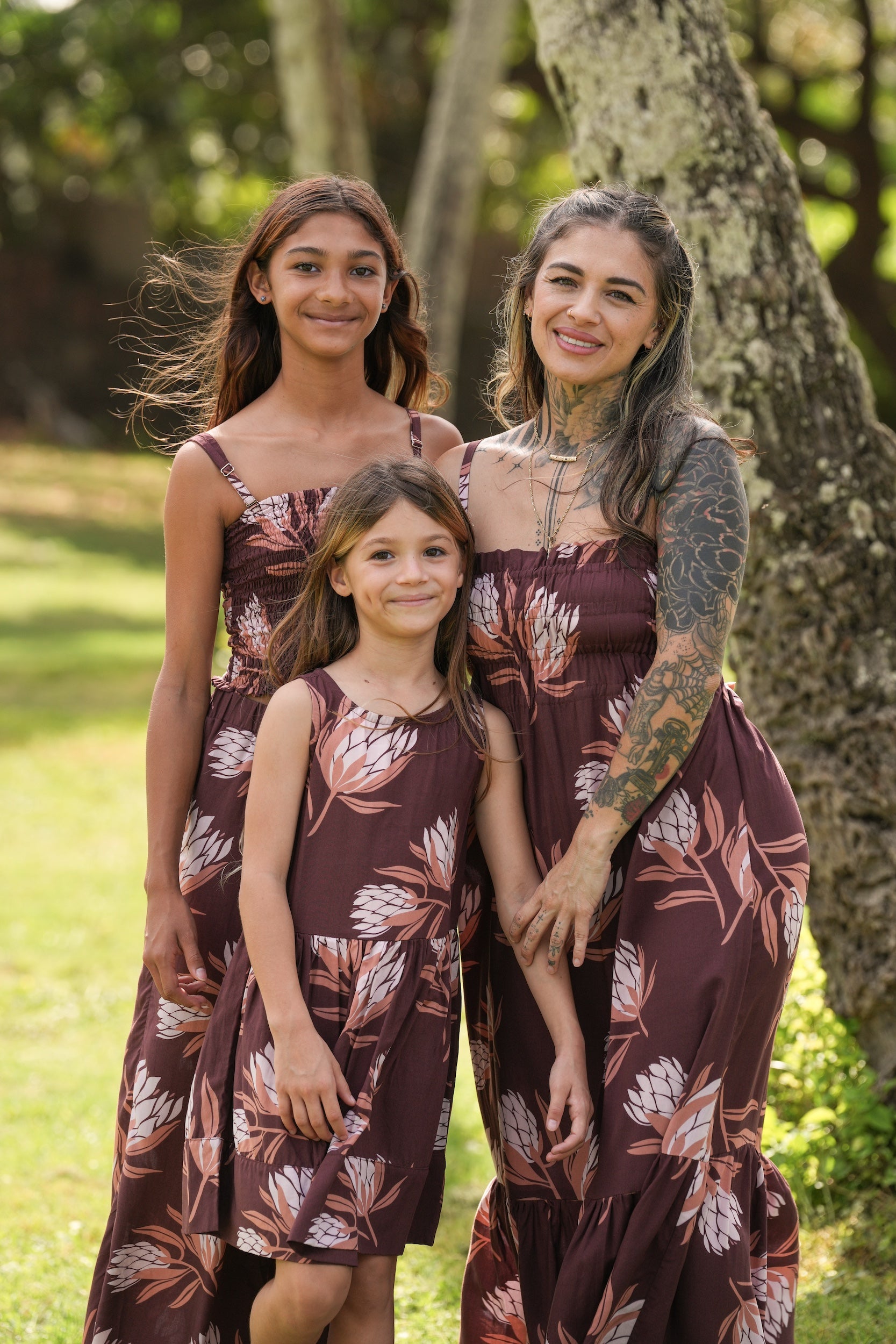 little girl wearing brown high neck, sleeveless dress with protea print