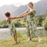 little girl wearing green smocked dress with native Hawaiian plants