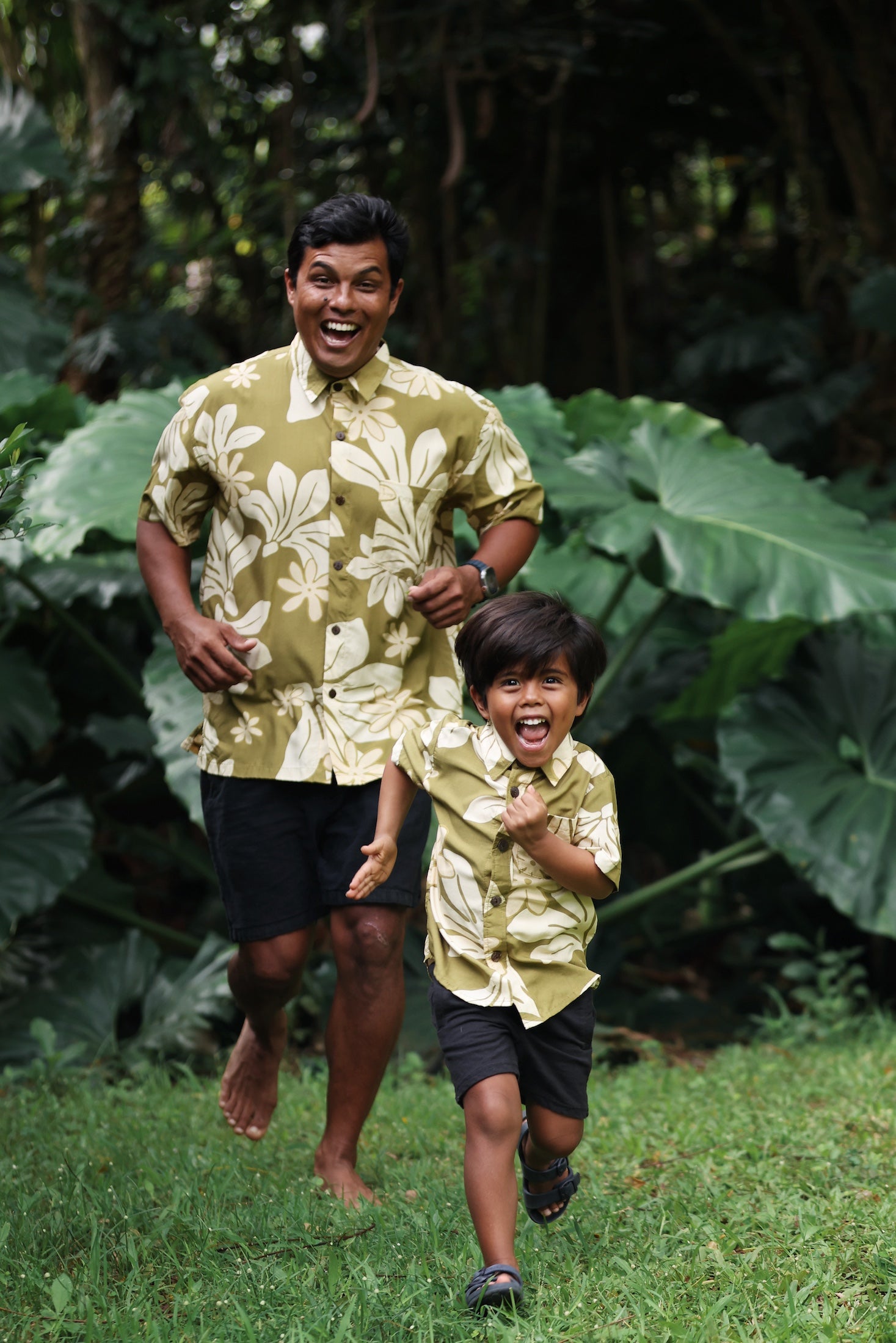 little boy wearing mini aloha button up shirt in green print and naupaka pattern