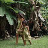 little girl wearing spaghetti strap dress in green print with naupaka pattern