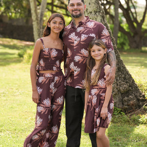little girl wearing brown high neck, sleeveless dress with protea print