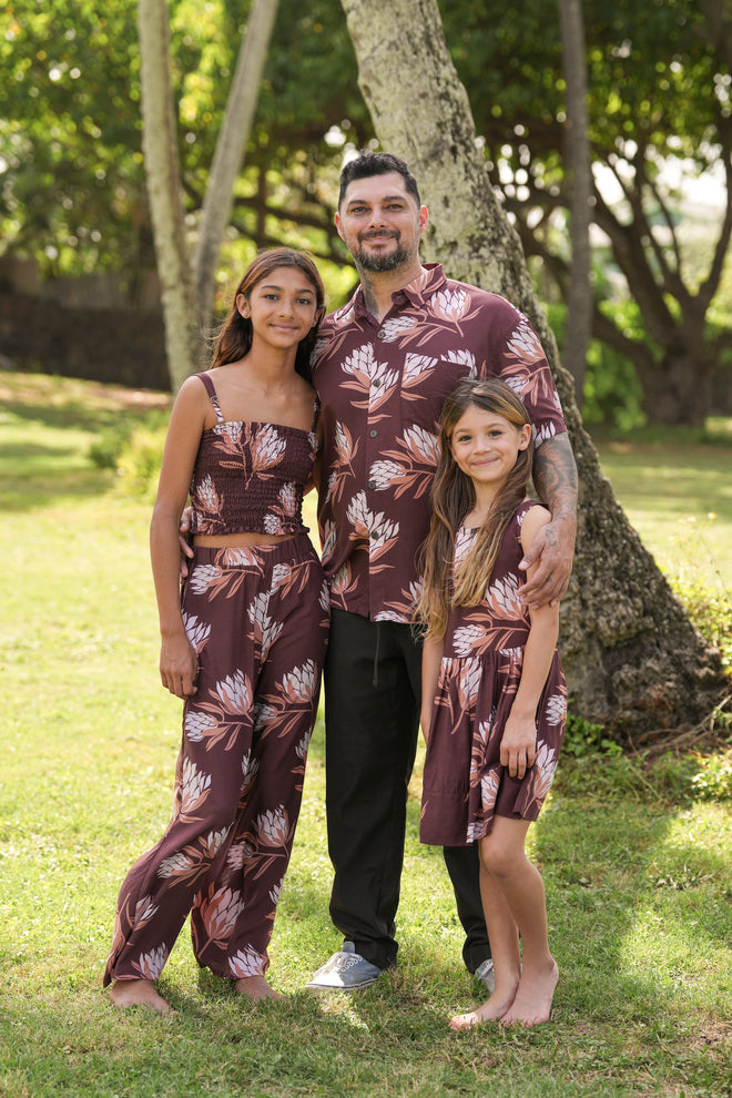 little girl wearing brown high neck, sleeveless dress with protea print
