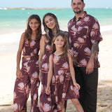 little girl wearing brown high neck, sleeveless dress with protea print