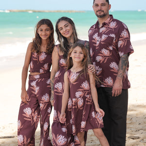 little girl wearing brown high neck, sleeveless dress with protea print
