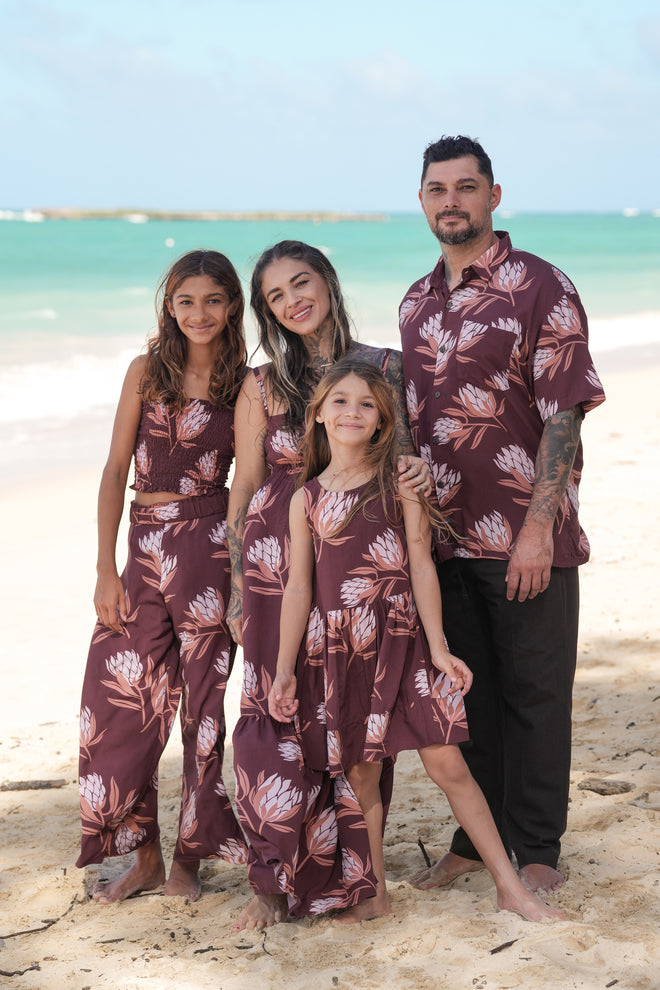 little girl wearing brown high neck, sleeveless dress with protea print
