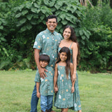 little girl wearing lush green tie back dress with puakenikeni print