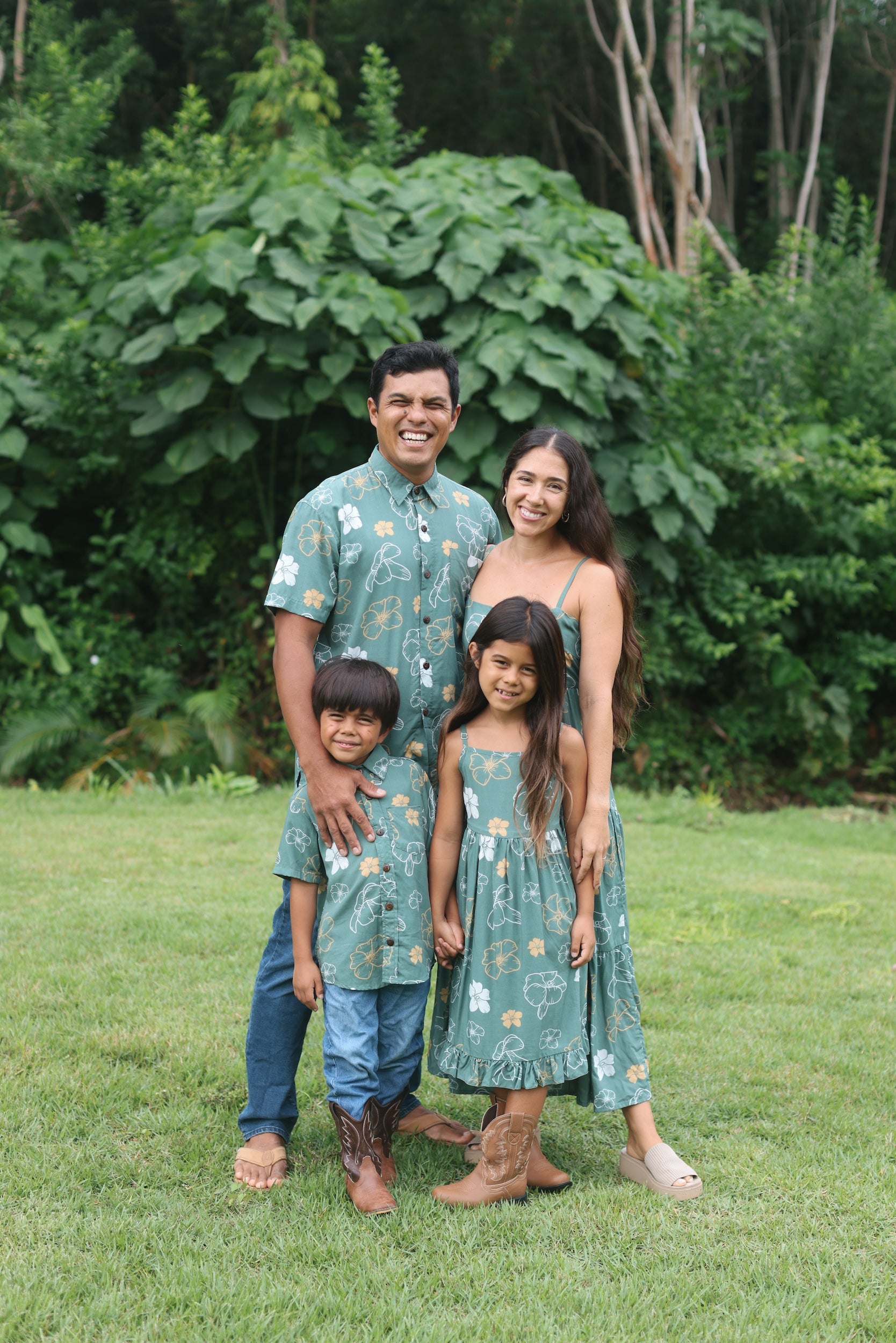little girl wearing lush green tie back dress with puakenikeni print