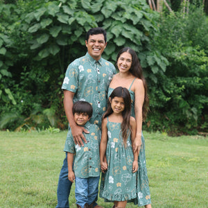 little girl wearing lush green tie back dress with puakenikeni print