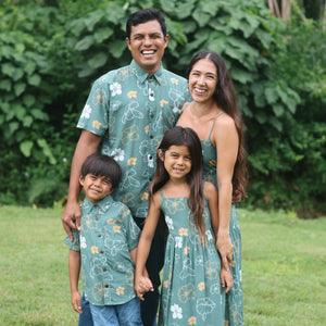 little boy wearing lush green aloha button up shirt with pua kenikeni print