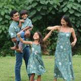 little girl wearing lush green tie back dress with puakenikeni print