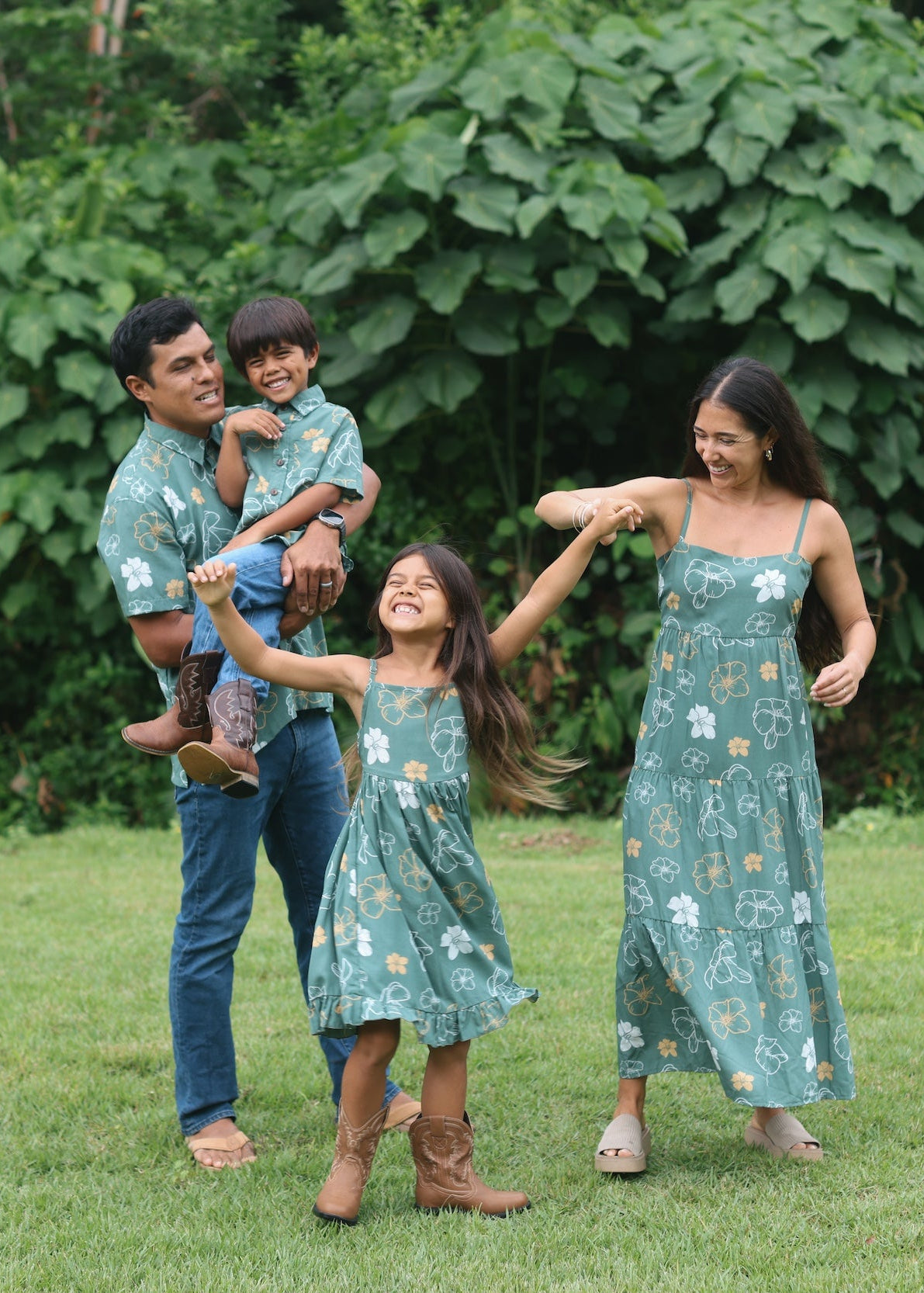 little girl wearing lush green tie back dress with puakenikeni print