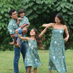 little girl wearing lush green tie back dress with puakenikeni print