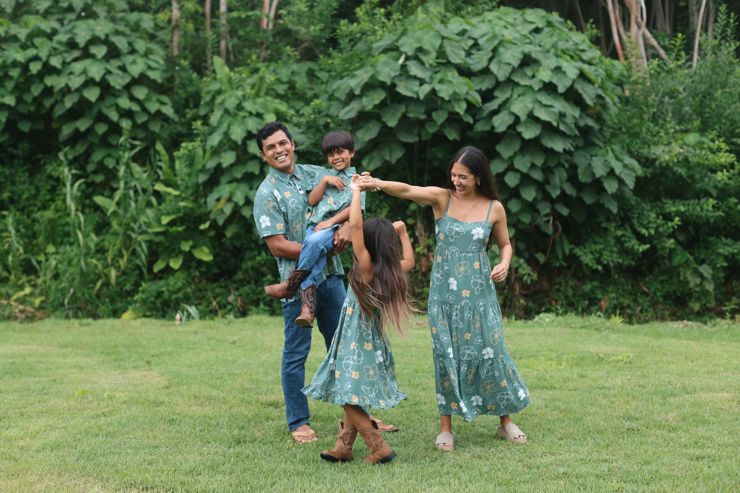 little boy wearing lush green aloha button up shirt with pua kenikeni print