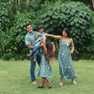 little boy wearing lush green aloha button up shirt with pua kenikeni print