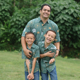 little boy wearing lush green aloha button up shirt with pua kenikeni print