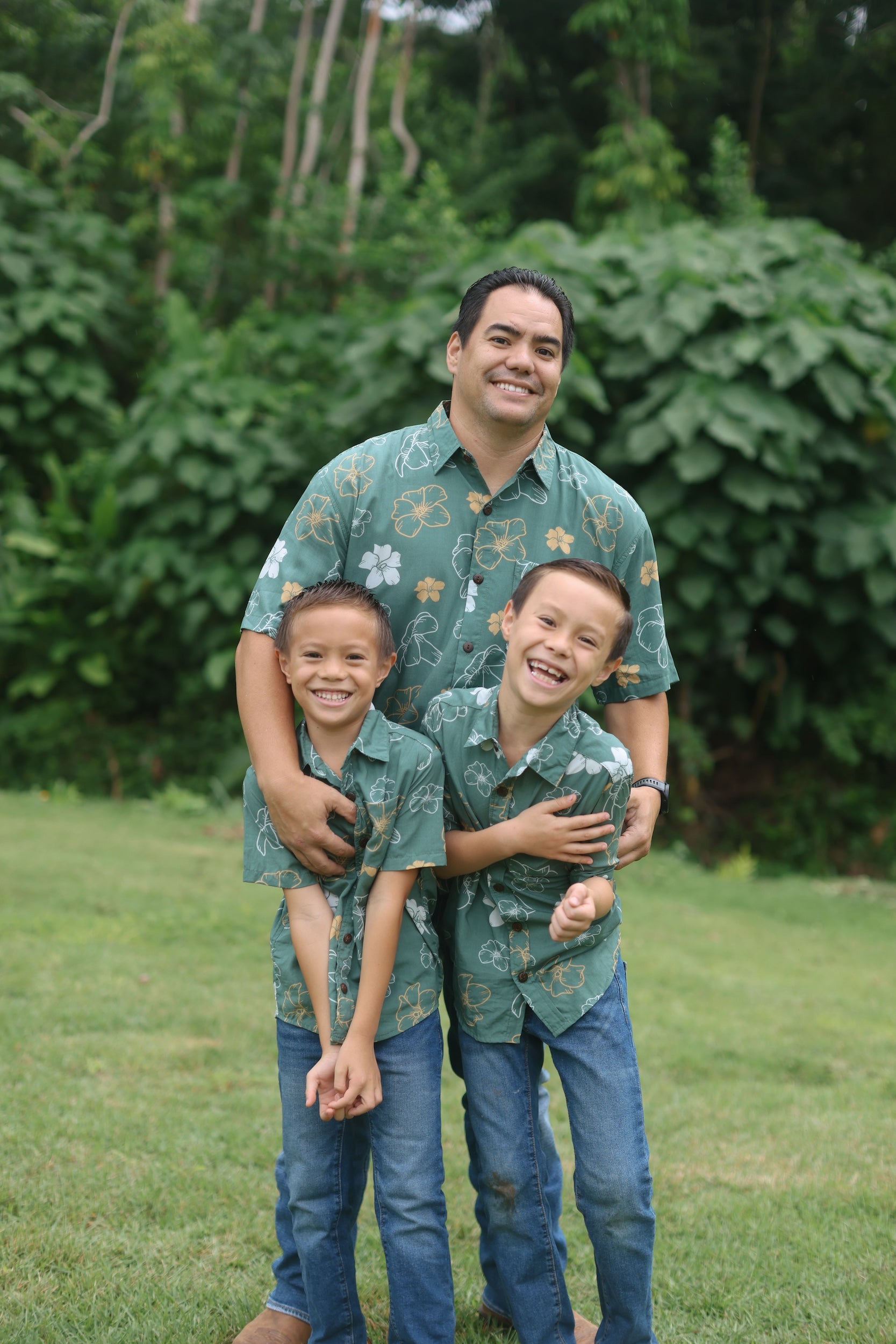 little boy wearing lush green aloha button up shirt with pua kenikeni print