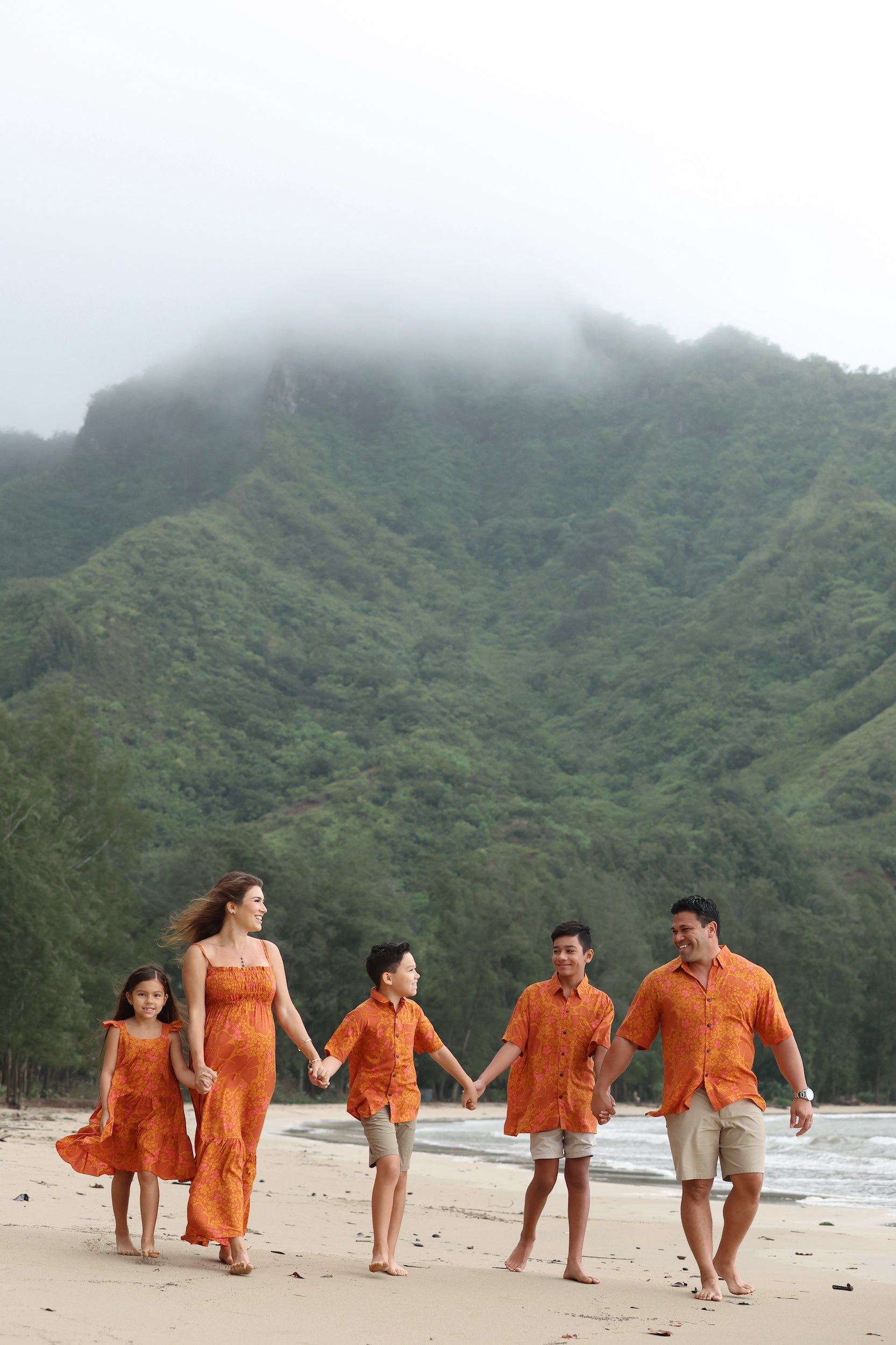 man with brown hair wearing an orange aloha button up shirt with puakenikeni print