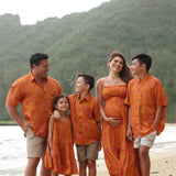 little boy wearing orange aloha button up shirt with puakenikeni print