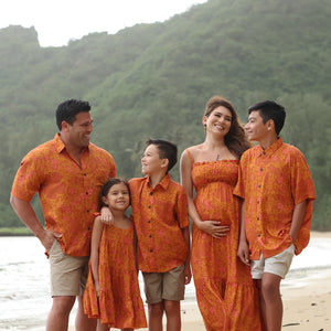 little boy wearing orange aloha button up shirt with puakenikeni print