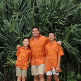 little boy wearing orange aloha button up shirt with puakenikeni print