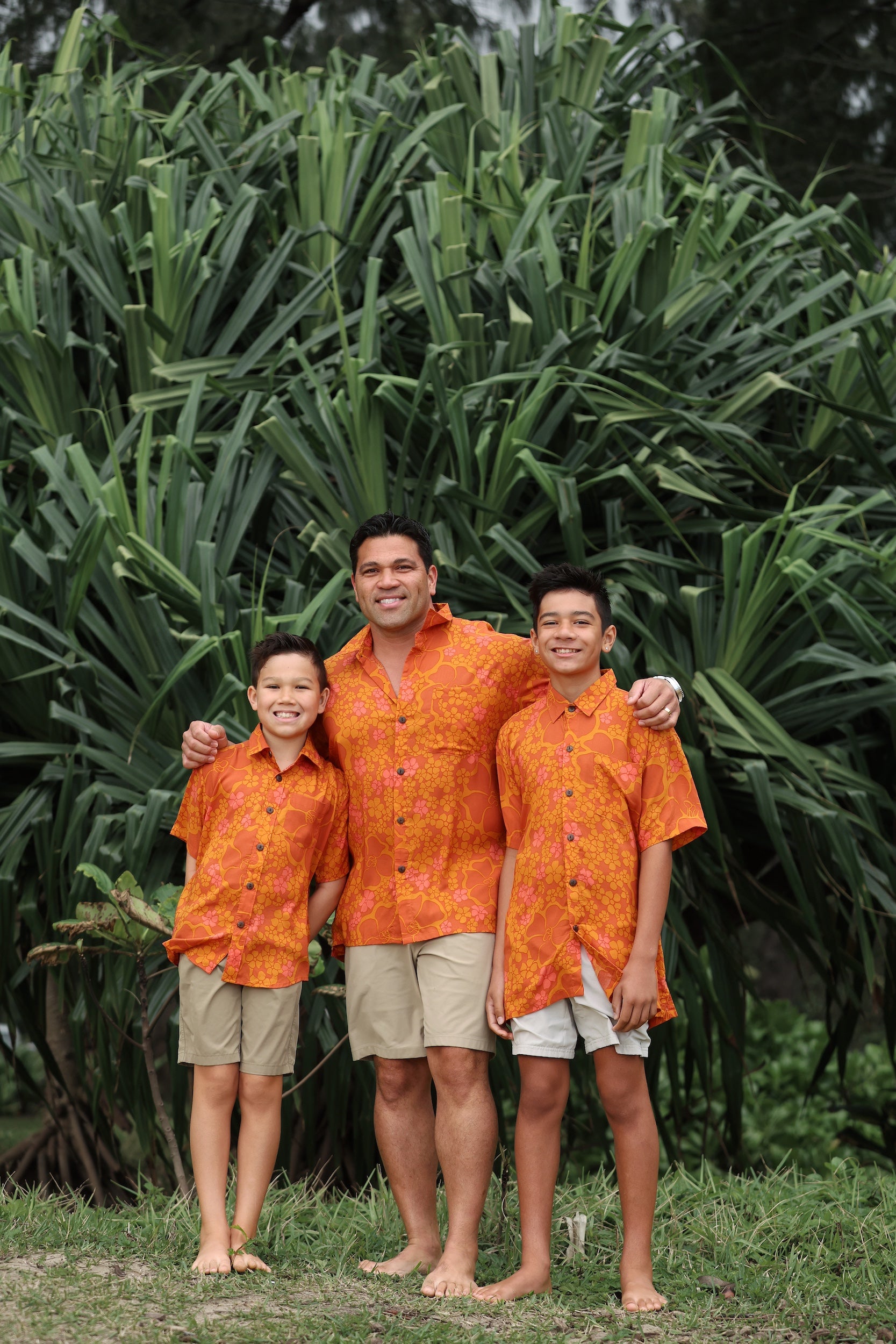 little boy wearing orange aloha button up shirt with puakenikeni print