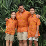 man with brown hair wearing an orange aloha button up shirt with puakenikeni print