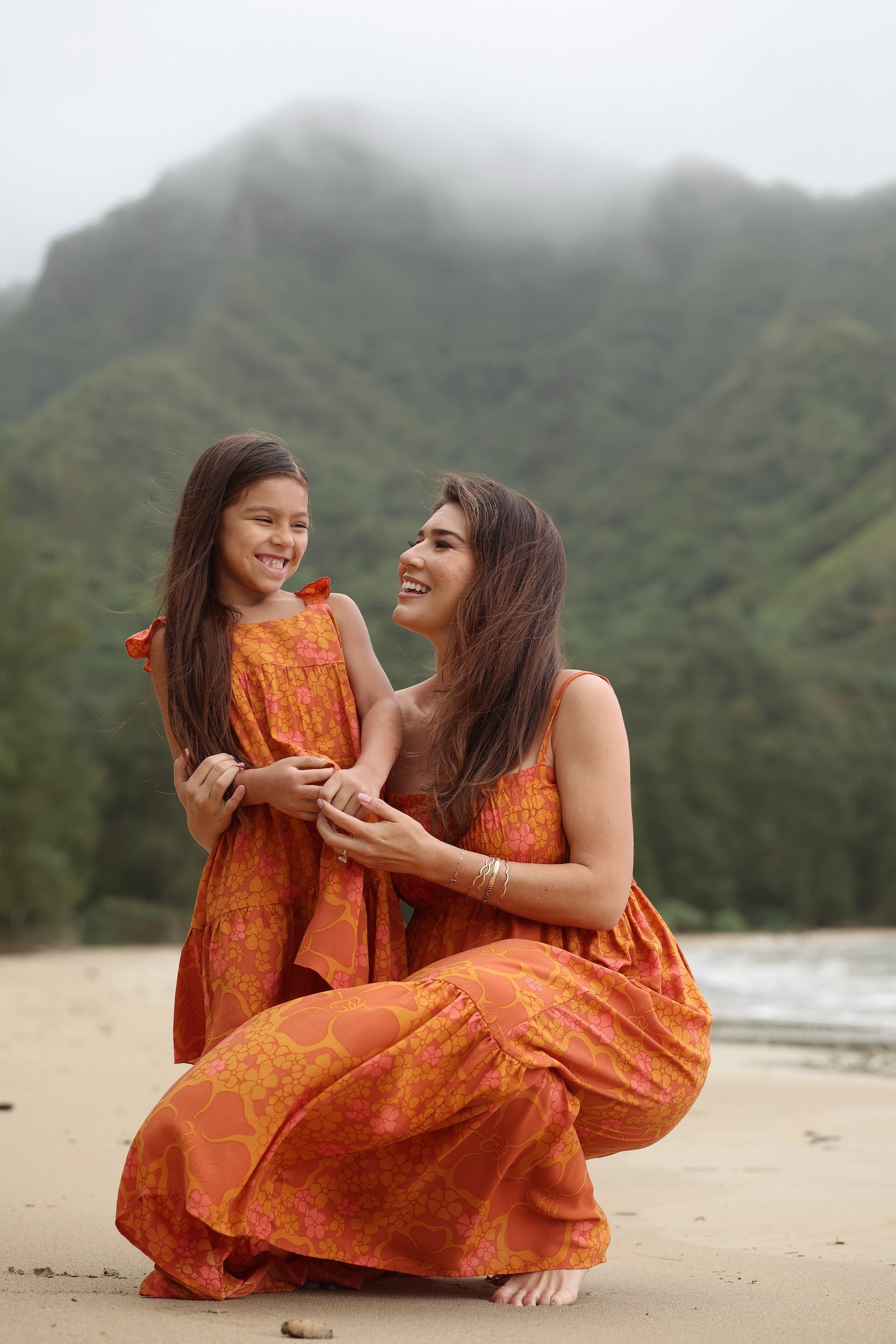 little girl wearing an orange flowy dress with puakenikeni print