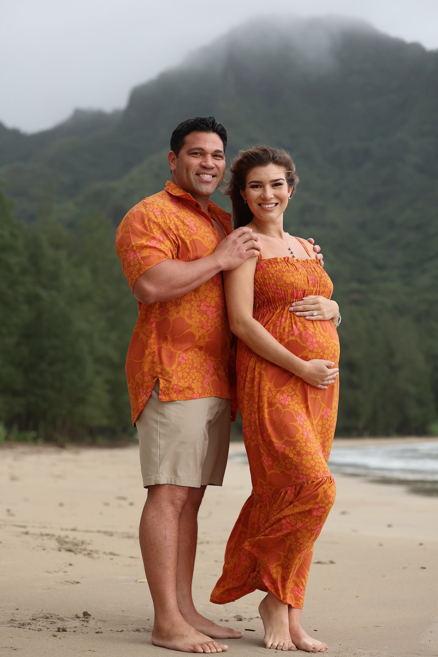 man with brown hair wearing an orange aloha button up shirt with puakenikeni print