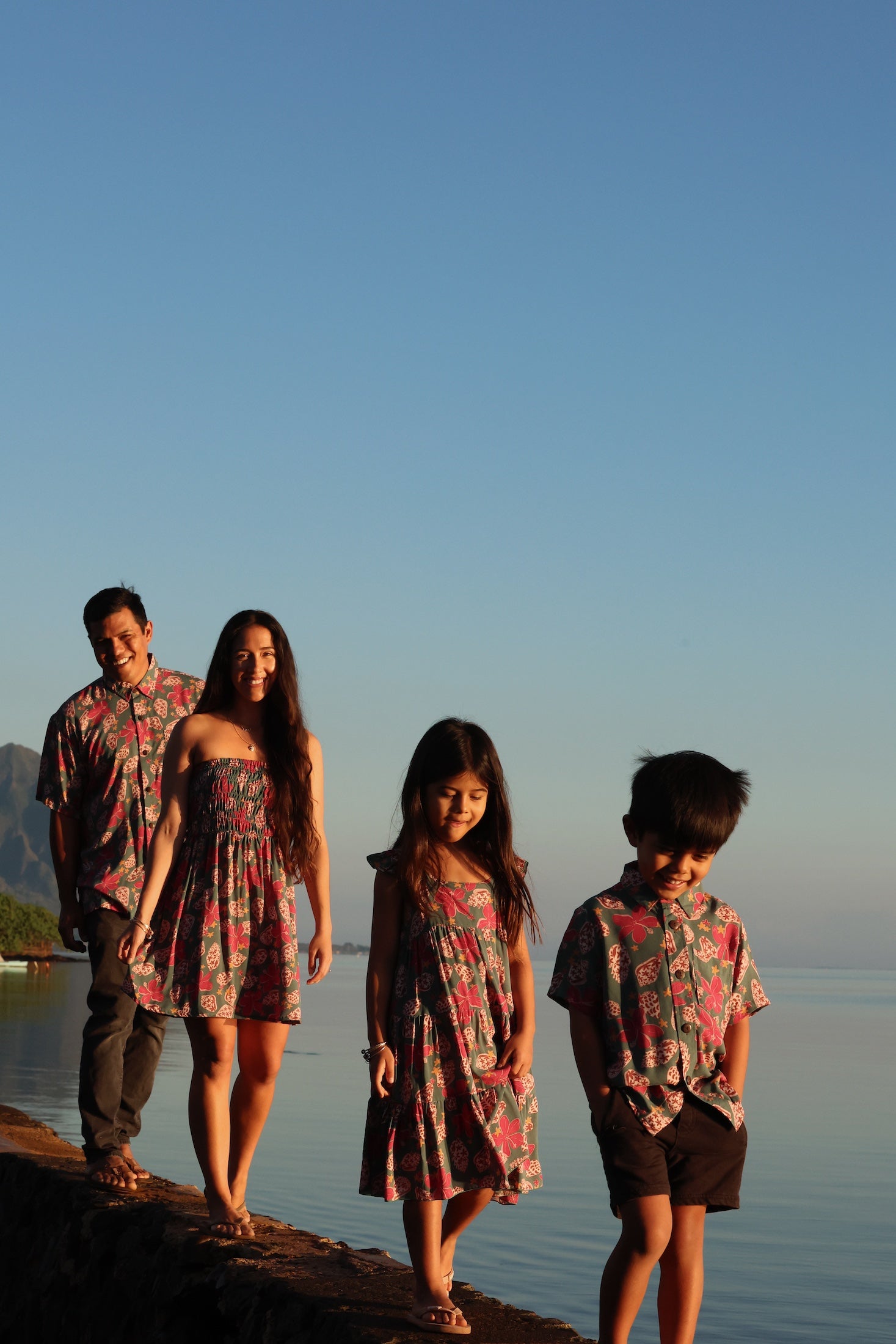 little boy wearing a teal aloha shirt with shell and pua print 