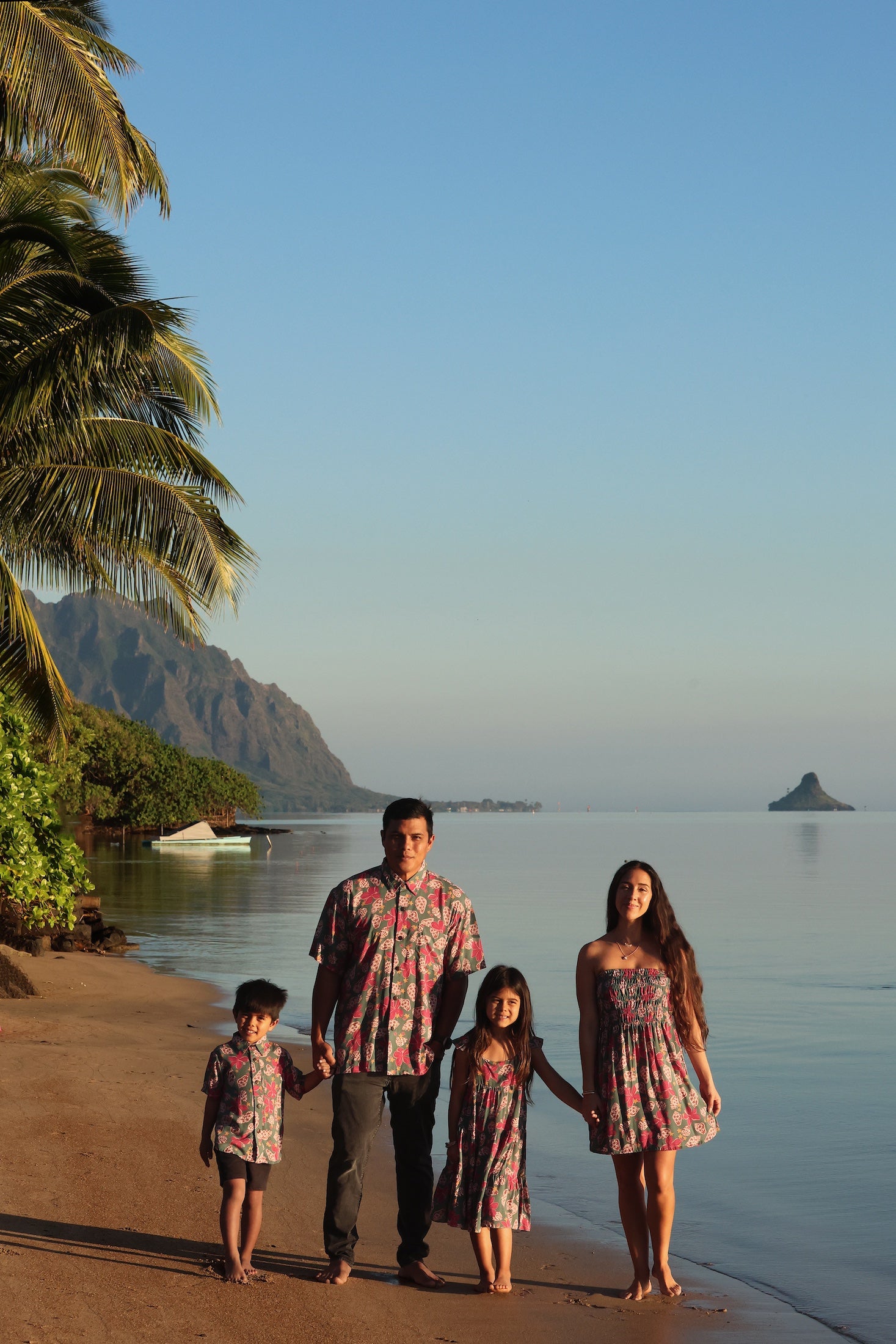 little boy wearing a teal aloha shirt with shell and pua print 