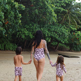little girl wearing long sleeve one piece bikini in blush and brown hibiscus print.