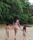 little girl wearing long sleeve one piece bikini in blush and brown hibiscus print.