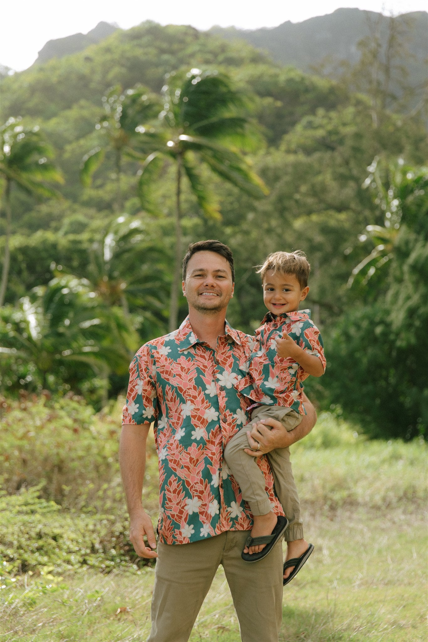 little boy wearing an aloha button up shirt with red ginger and tiare print