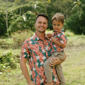 man wearing an aloha button up shirt with red ginger and tiare print