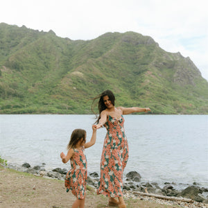 little girl wearing a knee length dress with red ginger and tiare print