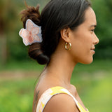 woman wearing a large peach and white orchid hair clip in hair