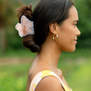 woman wearing a large peach and white orchid hair clip in hair