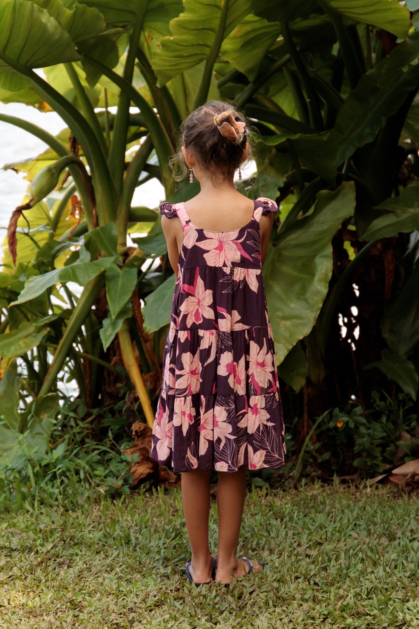 little girl wearing dark purple dress with flutter sleeve and orchid print