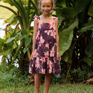 little girl wearing dark purple dress with flutter sleeve and orchid print