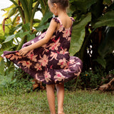 little girl wearing dark purple dress with flutter sleeve and orchid print